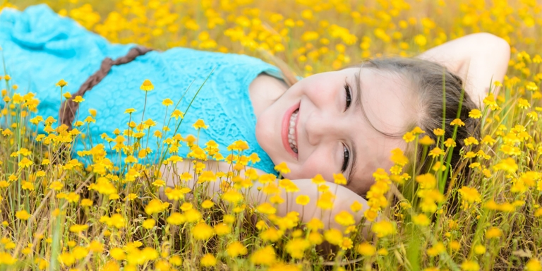 image of little girl lying in yellow flowers