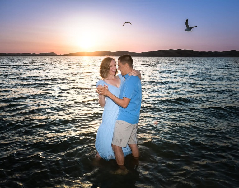 Couple in blue dancing in the water sun setting
