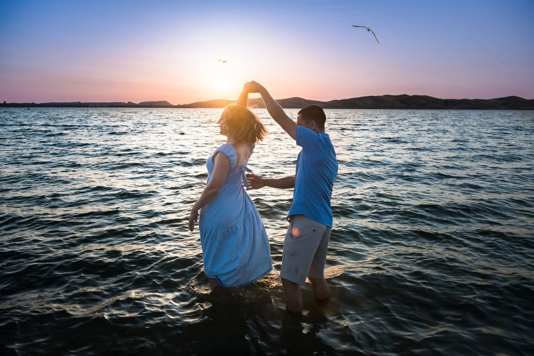 couple dancing woman spinning in sunset in lake