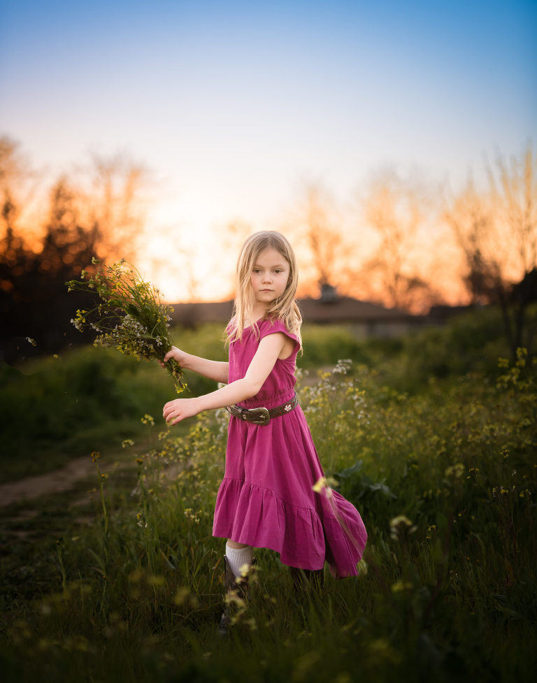 girl in bright pink dress dancing in the sunset