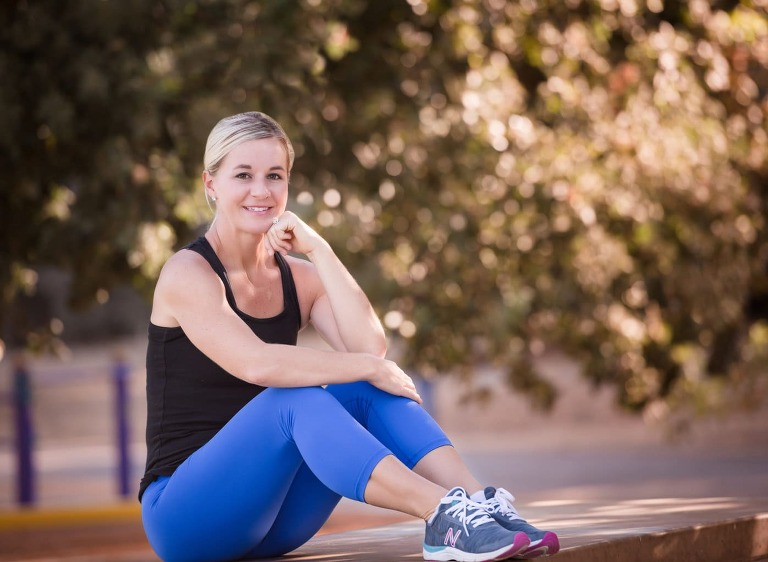 woman in work out clothes sitting on table in park